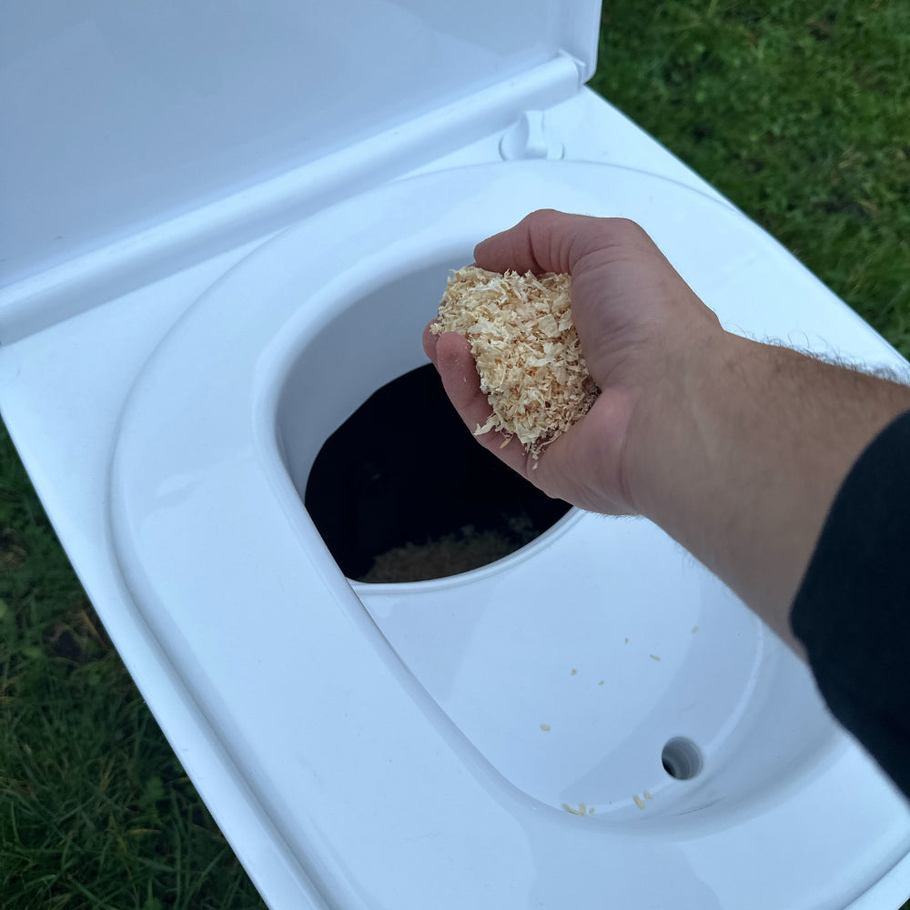 The laying method shown with Cuddy Lite. A hand is shown layering sawdust into the solids section of Cuddy Lite.