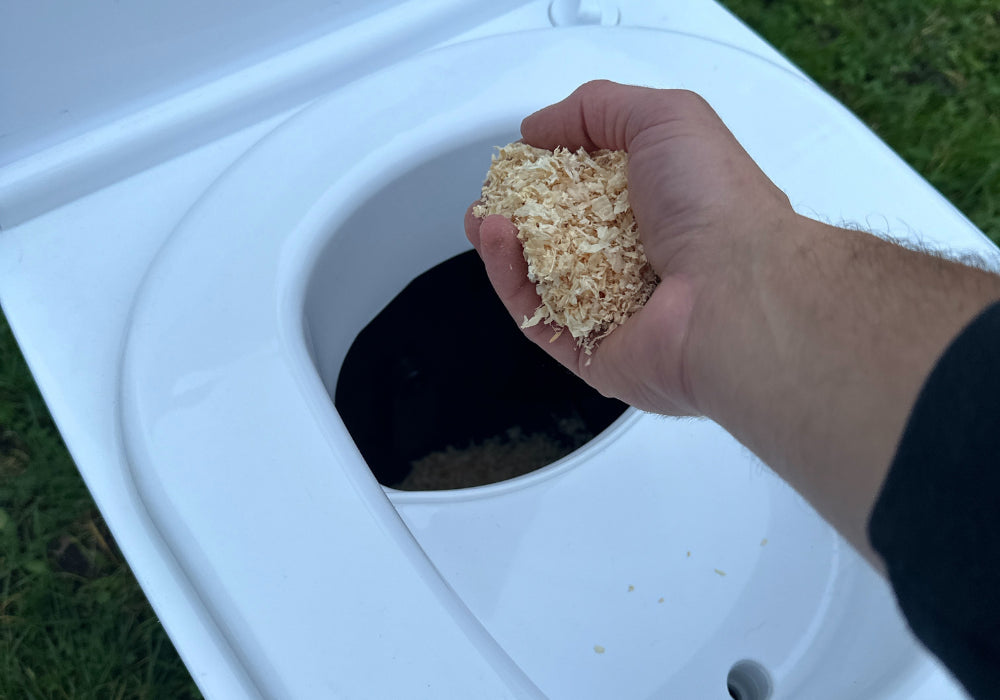 The laying method shown with Cuddy Lite. A hand is shown layering sawdust into the solids section of Cuddy Lite. 